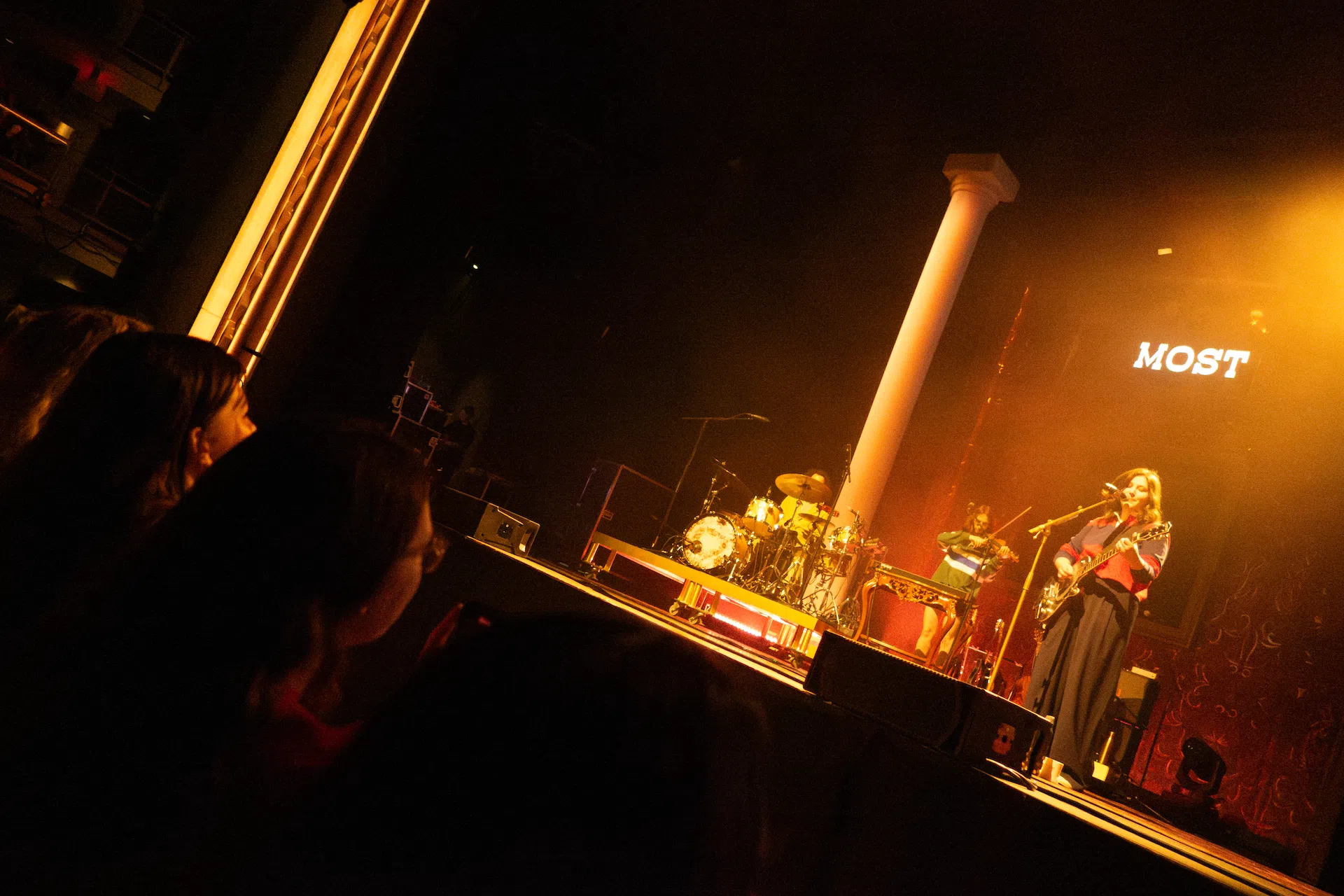 Wide shot of Lucy Dacus singing and playing guitar.